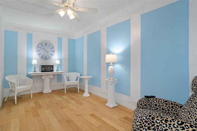 living area featuring a fireplace, ceiling fan, and light hardwood / wood-style flooring