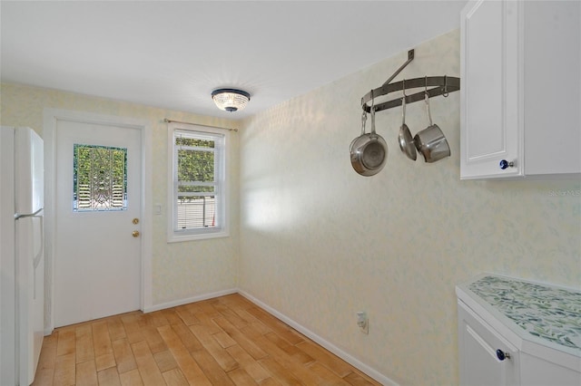 interior space with white cabinets, white fridge, and light hardwood / wood-style floors