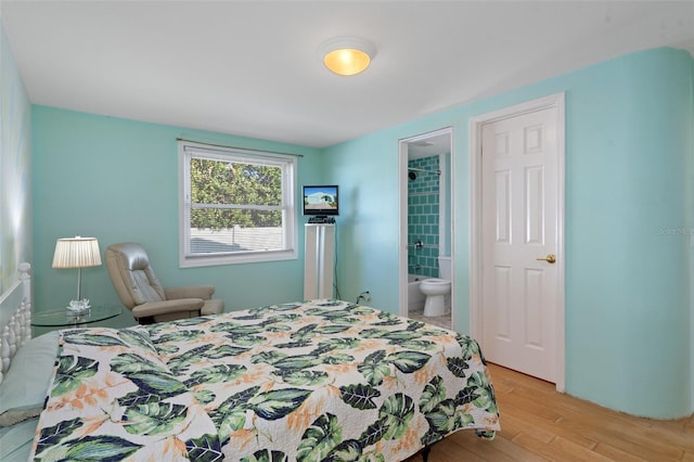 bedroom featuring connected bathroom and light hardwood / wood-style floors