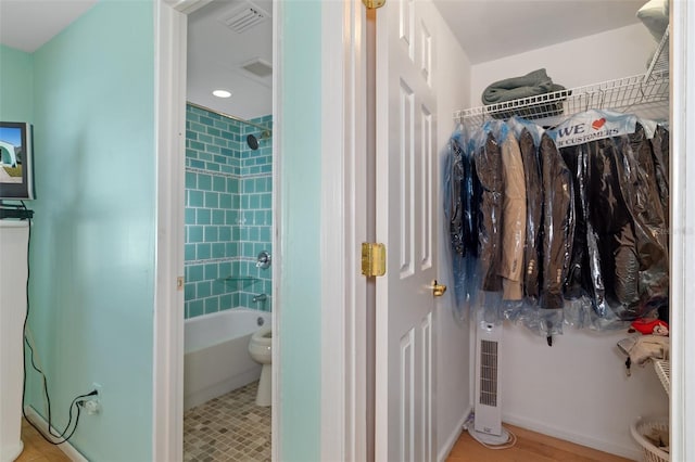 bathroom featuring tile patterned floors, toilet, and tiled shower / bath