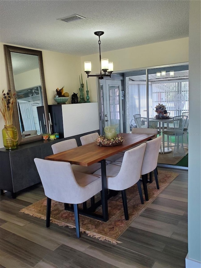 dining area featuring dark hardwood / wood-style flooring, a chandelier, and a textured ceiling