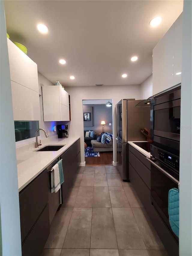 kitchen with tile patterned floors, sink, white cabinetry, and black appliances