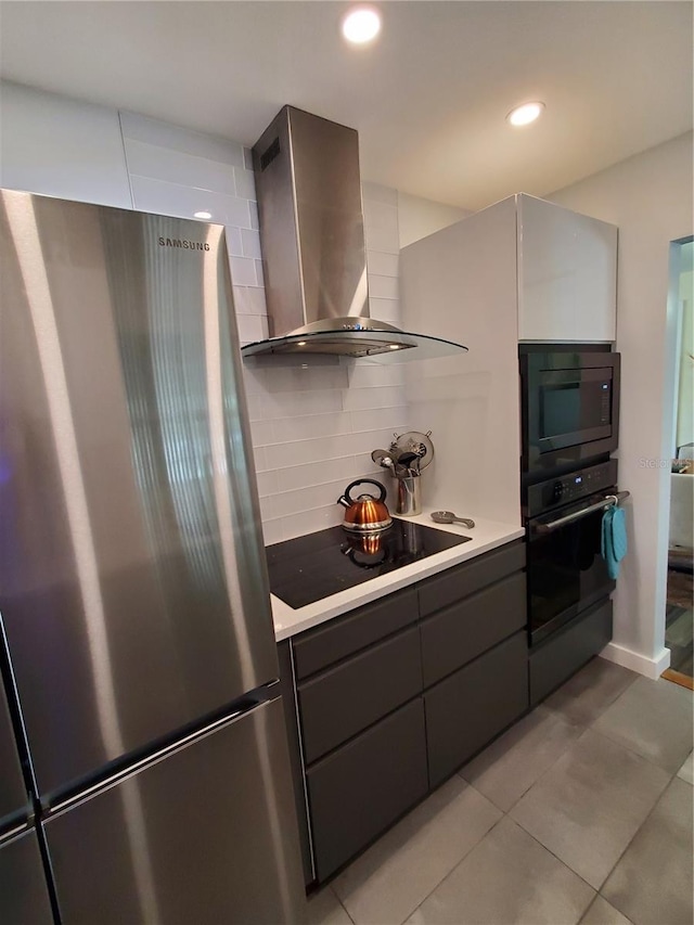 kitchen featuring backsplash, light tile patterned floors, black appliances, and wall chimney range hood