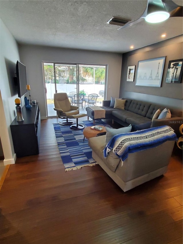 living room with a textured ceiling and dark hardwood / wood-style floors