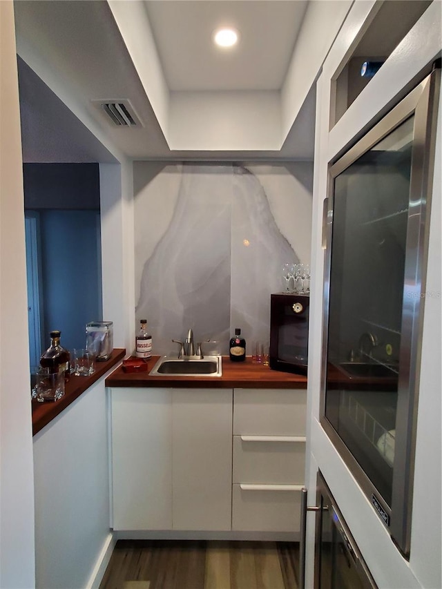 bar with white cabinetry, dark wood-type flooring, and sink