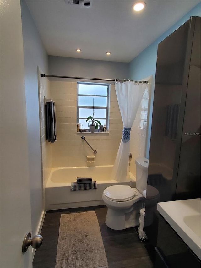 full bathroom featuring hardwood / wood-style floors, vanity, toilet, and shower / tub combo