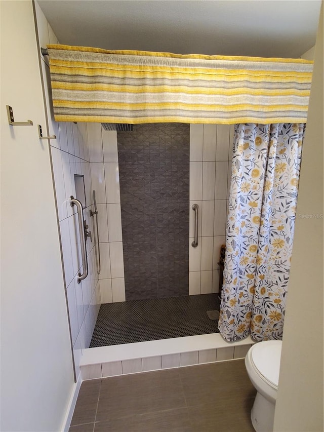 bathroom featuring toilet, tile patterned floors, and curtained shower