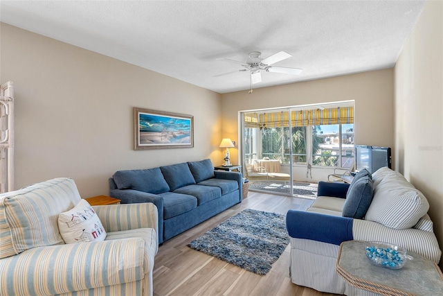 living room with a textured ceiling, light hardwood / wood-style flooring, and ceiling fan