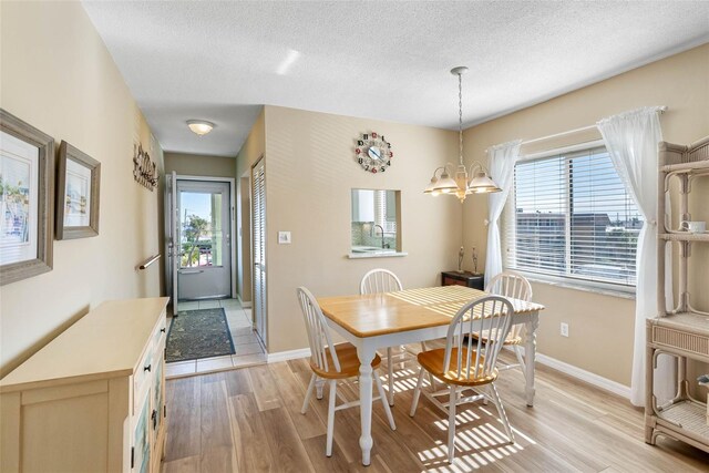 dining area featuring plenty of natural light, a textured ceiling, a chandelier, and light hardwood / wood-style flooring