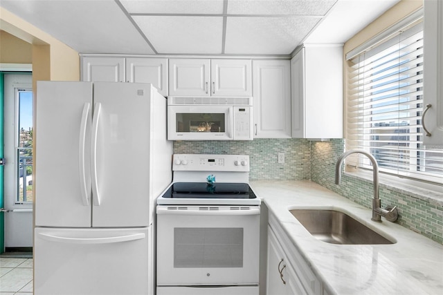 kitchen with white cabinets, light tile patterned flooring, white appliances, and sink