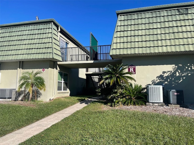 view of property exterior featuring a yard, a balcony, and central AC