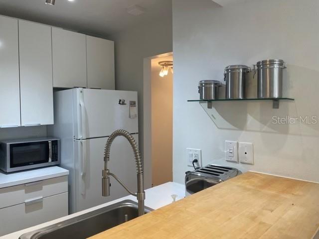 kitchen with white fridge, white cabinetry, and hardwood / wood-style flooring