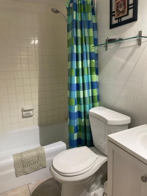 full bathroom featuring tile patterned flooring, vanity, toilet, and shower / bathtub combination with curtain