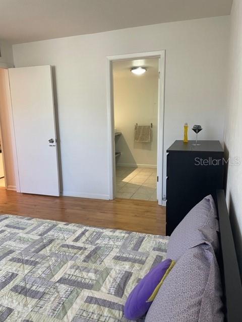 bedroom featuring connected bathroom and light hardwood / wood-style floors