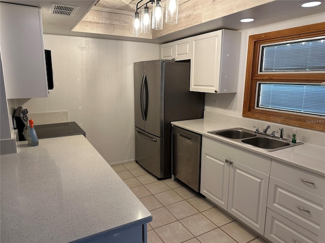 kitchen with appliances with stainless steel finishes, sink, a notable chandelier, white cabinetry, and light tile patterned flooring