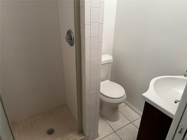 bathroom with toilet, a tile shower, vanity, and tile patterned floors