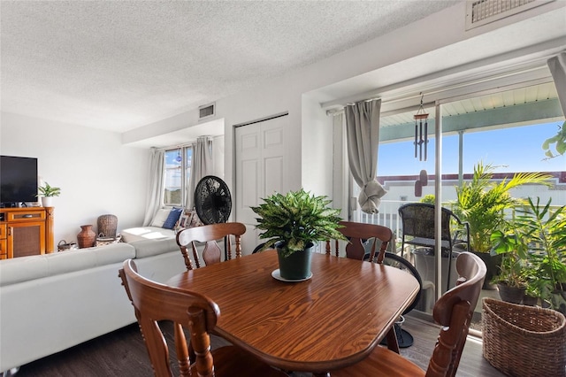 dining room featuring a textured ceiling, dark hardwood / wood-style floors, and a wealth of natural light