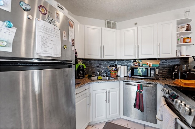 kitchen featuring white cabinets, light tile patterned floors, a textured ceiling, and stainless steel appliances