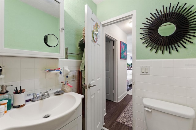 bathroom with wood-type flooring, vanity, toilet, and tile walls