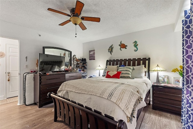 bedroom featuring ceiling fan, light hardwood / wood-style floors, and a textured ceiling