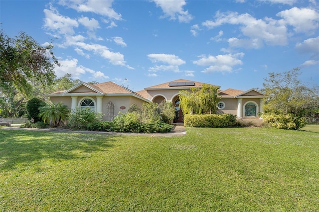 mediterranean / spanish-style home featuring a front yard and solar panels