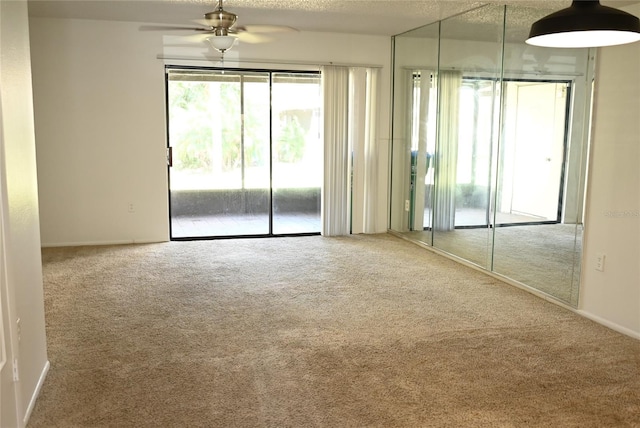 carpeted spare room featuring a textured ceiling and ceiling fan