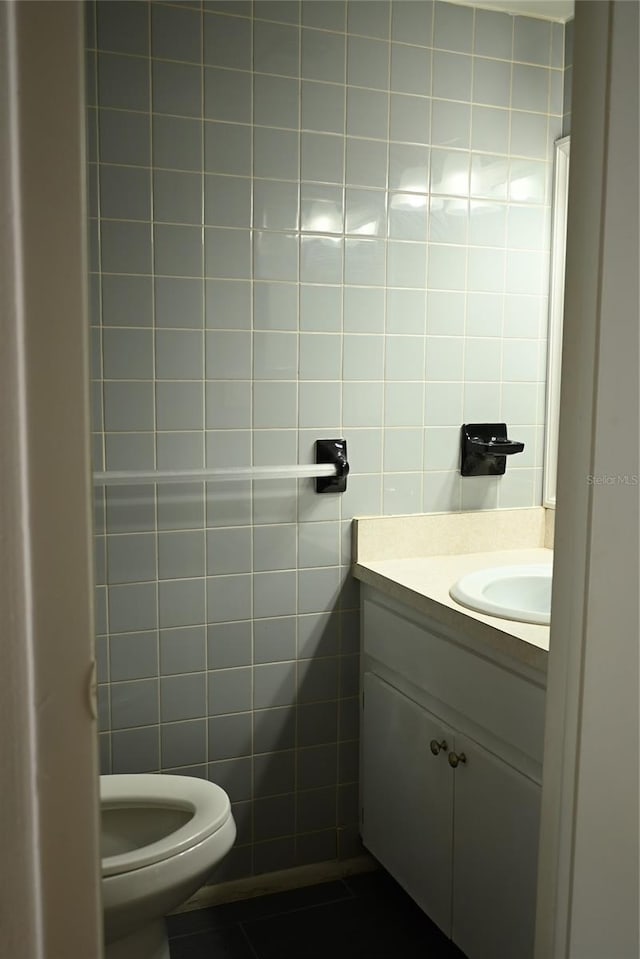 bathroom featuring tile patterned floors, vanity, toilet, and tile walls