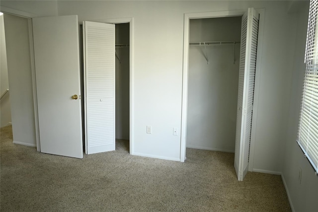 unfurnished bedroom with light carpet and two closets