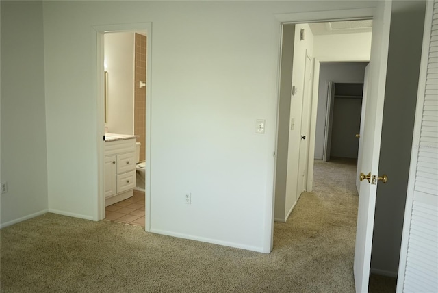 unfurnished bedroom featuring ensuite bathroom and light carpet