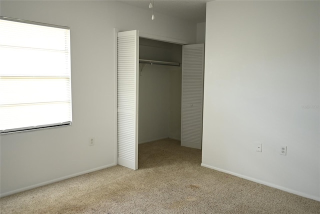 unfurnished bedroom with a closet, light carpet, and multiple windows