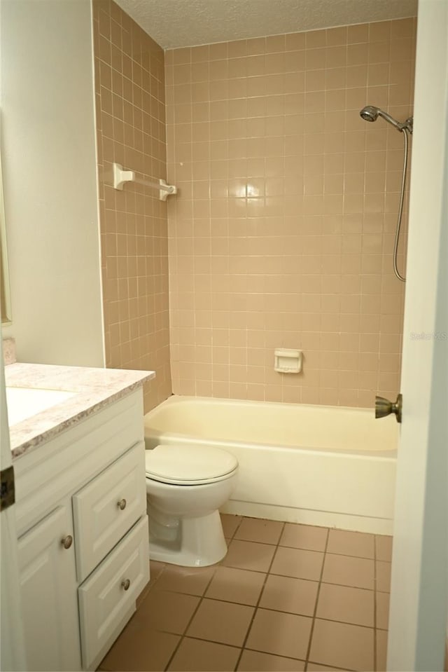 full bathroom featuring vanity, tile patterned floors, tiled shower / bath, toilet, and a textured ceiling