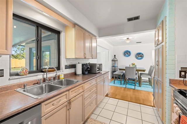 kitchen with sink, decorative backsplash, light brown cabinetry, light tile patterned flooring, and appliances with stainless steel finishes