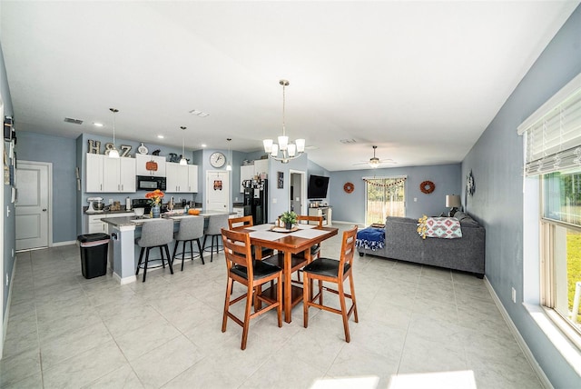 tiled dining area with a wealth of natural light and ceiling fan with notable chandelier