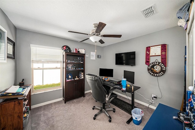 carpeted home office with ceiling fan and a textured ceiling