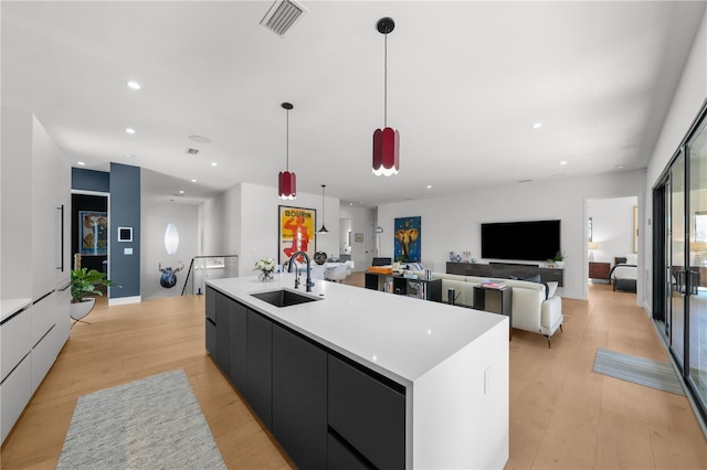 kitchen with light wood-type flooring, sink, pendant lighting, and a large island