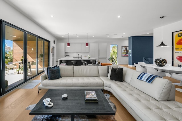 living room featuring plenty of natural light, sink, and light hardwood / wood-style flooring