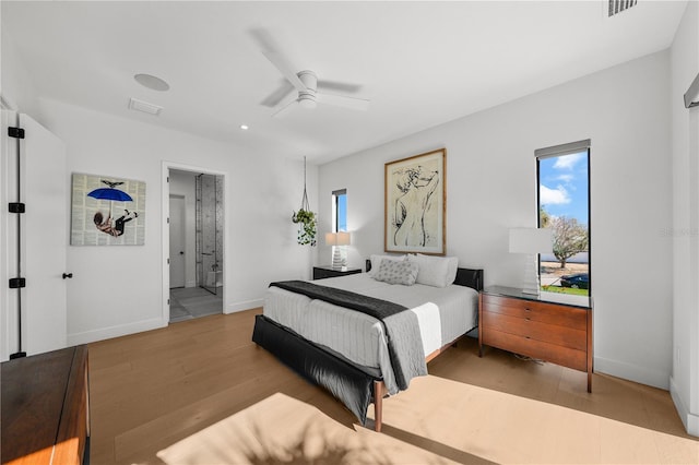 bedroom with ceiling fan, ensuite bath, and light wood-type flooring