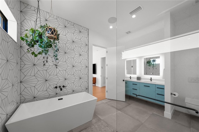 bathroom with a bathtub, vanity, tile walls, and concrete floors