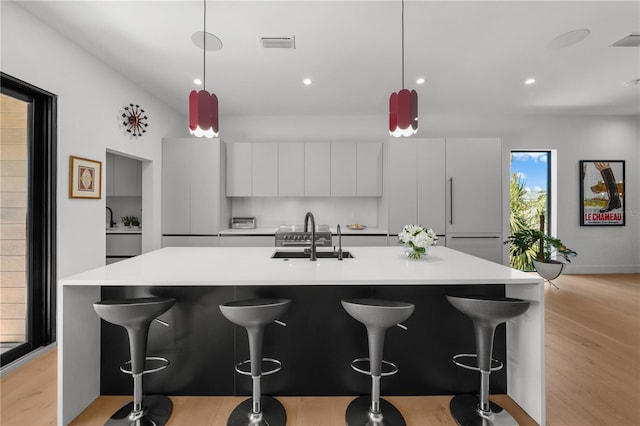 kitchen with sink, hanging light fixtures, and an island with sink