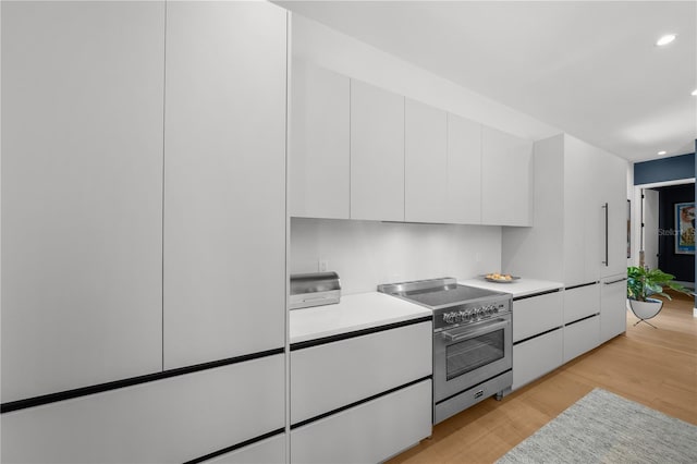 kitchen featuring white cabinetry, high end stainless steel range, and light hardwood / wood-style flooring