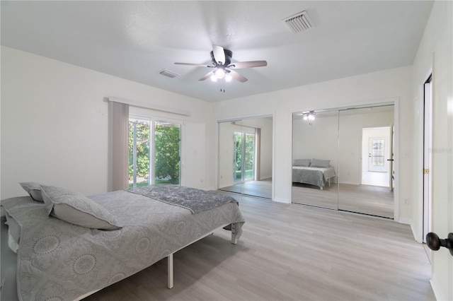 bedroom featuring ceiling fan, light wood-type flooring, and two closets