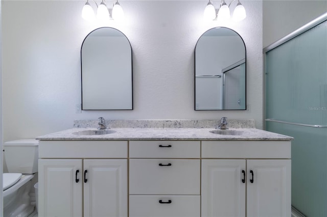 bathroom with a shower with door, vanity, and toilet