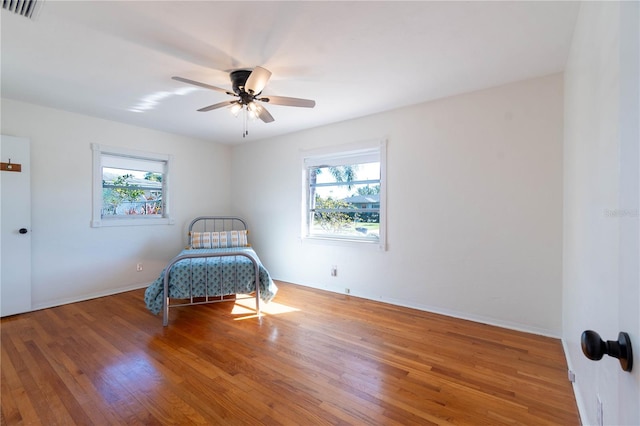 unfurnished bedroom with hardwood / wood-style floors, ceiling fan, and multiple windows