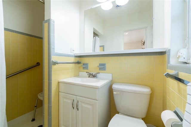 bathroom with vanity, toilet, and tile walls