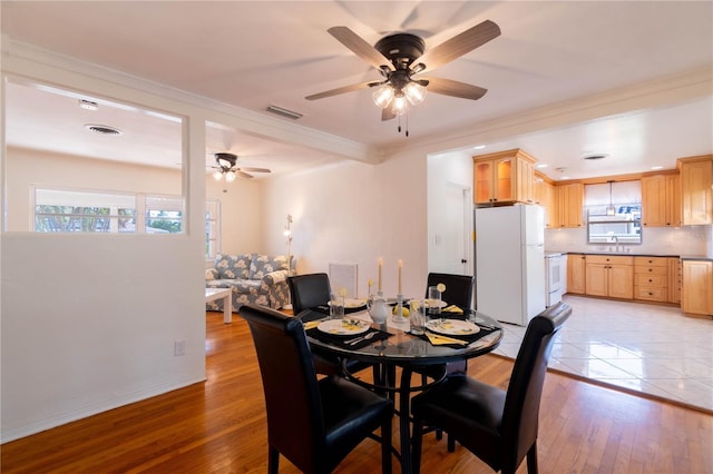 dining area featuring light hardwood / wood-style flooring, ceiling fan, crown molding, and sink