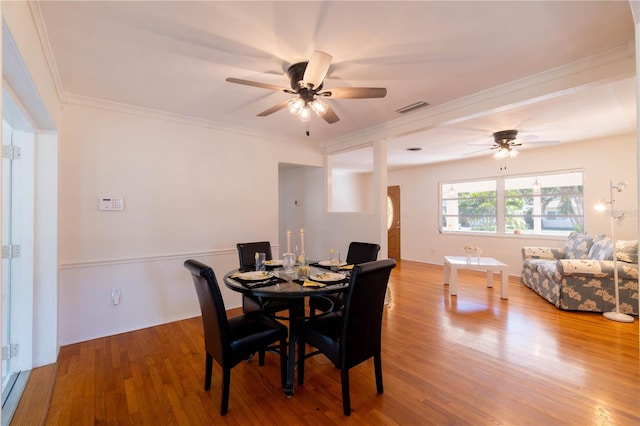 dining space with wood-type flooring, ceiling fan, and crown molding