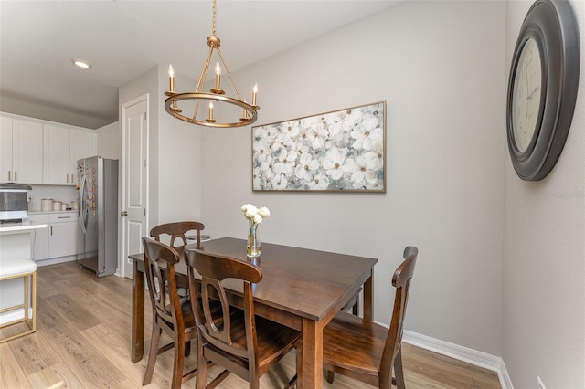 dining area featuring a notable chandelier, light wood-style flooring, and baseboards