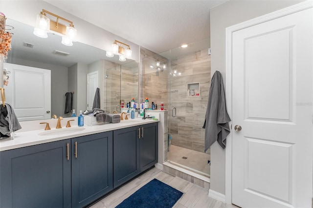 bathroom featuring vanity, a textured ceiling, and walk in shower