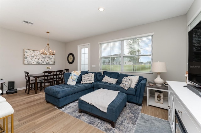 living area with a notable chandelier, baseboards, visible vents, and light wood-type flooring