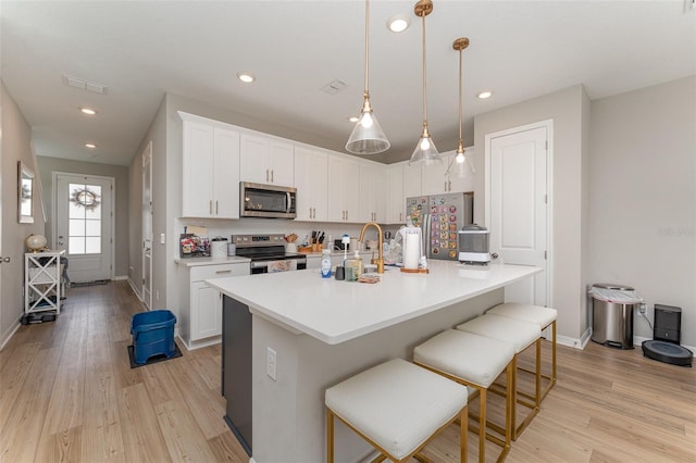 kitchen featuring light wood finished floors, decorative backsplash, white cabinets, and appliances with stainless steel finishes